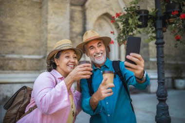 Yaşlı evli bir çift kahve molasındayken selfie çekiyor. Yeni şehri keşfeden turistler.