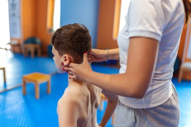 Küçük bir çocuğun terapi seansı. Tek bacağının üzerinde duruyor, leğen kemiğini ve omurgasını düzeltiyor..