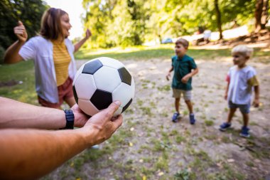 Dört kişilik aile parkta futbol oynuyor..