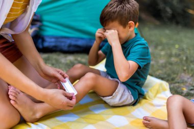 Annem küçük bir çocuğa bandaj yapıyor. Çocuk kamp yaparken yaralanmış..