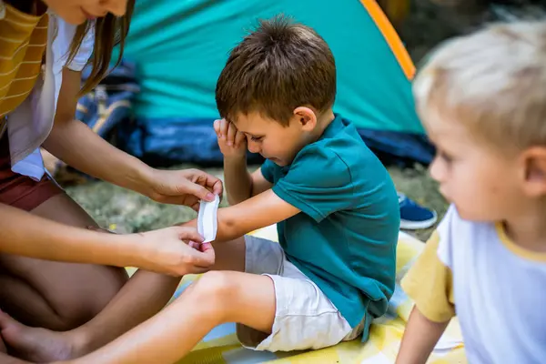 stock image Mom putting a bandage on a little boy. Boy hurt himself on a camping.