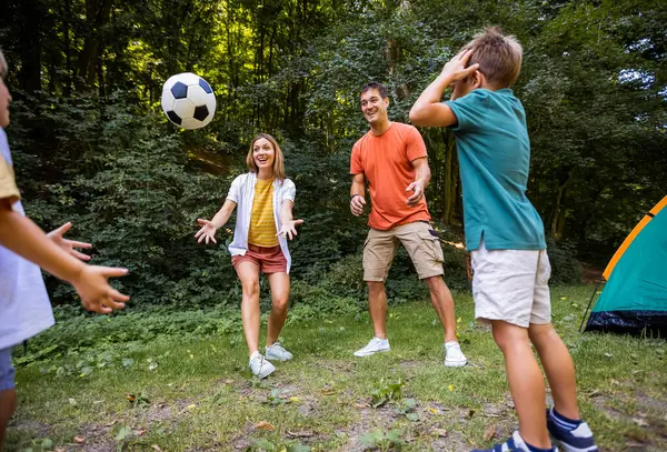 Dört kişilik aile parkta futbol oynuyor..