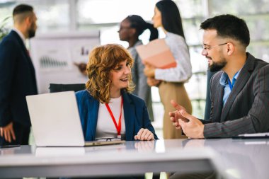 İki iş adamı ofiste dizüstü bilgisayarlar ve tabletler üzerinde birlikte çalışıyor..