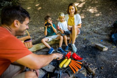 Dört kişilik aile parkta piknik yapıyor. Babam sebze ve et pişirir. Doğayı keşfetmeye ara verdim..