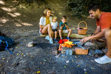 Dört kişilik aile parkta piknik yapıyor. Babam sebze ve et pişirir. Doğayı keşfetmeye ara verdim..