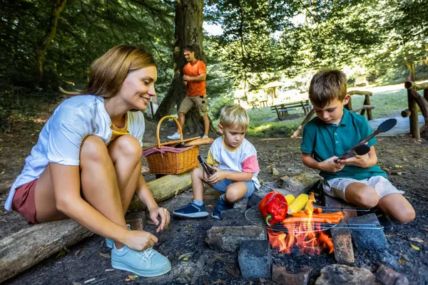 İki oğul doğada et ve sebze ızgara yapmayı öğreniyor. Babam yakacak odun seçiyor. Doğa, keşif ve kamp konsepti.
