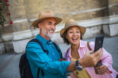 Yaşlı evli bir çift kahve molasındayken selfie çekiyor. Yeni şehri keşfeden turistler.