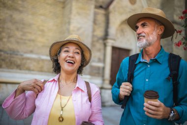 Şehir merkezinde kahve içen olgun evli bir çift. Şehri gezen turistler.