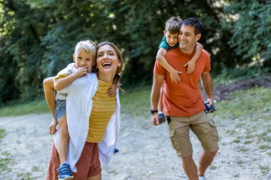 Anne ve baba ve oğulları parkta oynuyorlar. Sırtlarında taşıyorlar..
