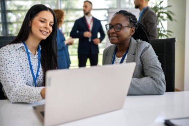 Dizüstü bilgisayarlarda birlikte çalışan iki iş kadını..