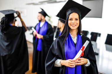 Arkadaşlarının önünde diplomasını tutan Toga 'lı bir öğrencinin portresi.. 