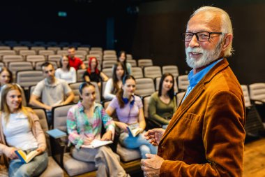 Amfitiyatroda öğrencilere ders veren yaşlı erkek profesörün portresi.