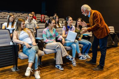 Bir konferansta öğrencilerinin sorularını yanıtlayan yaşlı bir profesör..