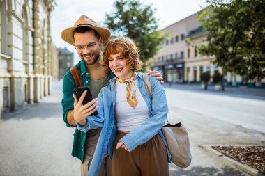 Genç çift, tatilde, yeni şehri keşfediyorlar ve telefonlarını kaybolmamaları için GPS olarak kullanıyorlar..