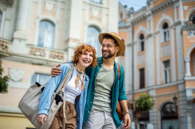 Genç çift, şehir merkezinde yürürken ve kucaklaşırken yeni şehri keşfediyor. Seyahat konsepti.
