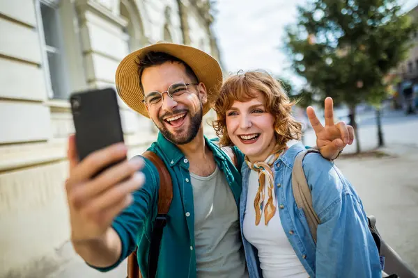 Şehir merkezinde selfie çeken genç bir çift. Seyahat ve keşif konsepti.