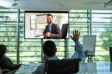 Video konferans görüşmesi. Büyük ekrandaki CEO, meslektaşlarına sorularını cevaplıyor..