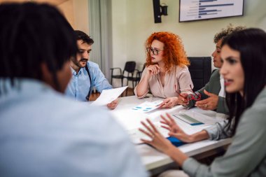 Bir grup iş adamı toplantı odasında brifing veriyor. Modern bir iş yerinde birlikte çalışan iş adamları. Şirketteki istatistik ve grafikler hakkında konuşmak.
