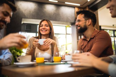 Kahve dükkanında gülen bir grup arkadaş..