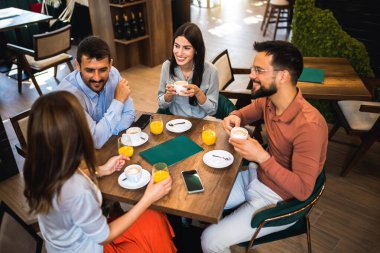 Bir grup arkadaş kafede birlikte gülüyorlar. Portakal suyu içip birlikte takılıyorlar..