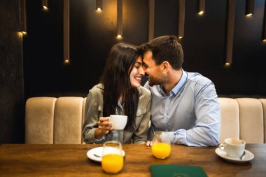 Genç bir çift kahve dükkanında buluşuyor. Birbirinize sevgiyle bakın. Kahve ve portakal suyu içerek..