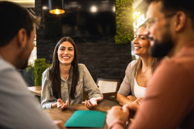 Bir grup arkadaş kafede oturuyor ve birbirleriyle konuşuyorlar..