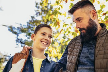Baba ve oğul renkli parkta kaynaşıyorlar. Sonbahar günü.