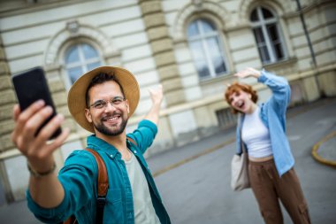 Şehir merkezinde selfie çeken genç bir çift. Seyahat ve keşif konsepti.