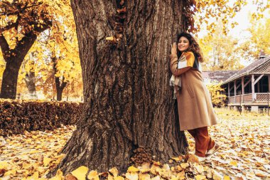 Parkta ağaca sarılan mutlu İspanyol kadın. Gezegeni ve çevreyi sevmek.