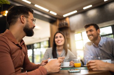 Bir grup arkadaş kafede birlikte gülüyorlar. Portakal suyu içip birlikte takılıyorlar..