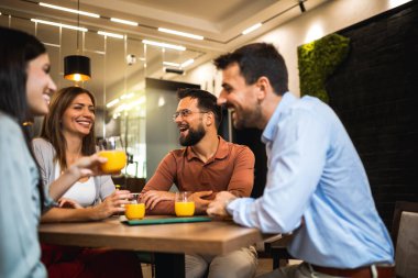 Bir grup arkadaş kafede oturup portakal suyu içiyor..