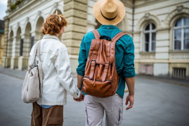 Kızıl kız arkadaşı ve erkek arkadaşı yeni şehri keşfederken el ele tutuşuyorlar ve tatillerinde paralara ve binalara bakıyorlar..