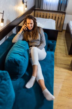 Mavi koltukta oturan ve telefonuyla konuşan güzel bir kızın portresi..
