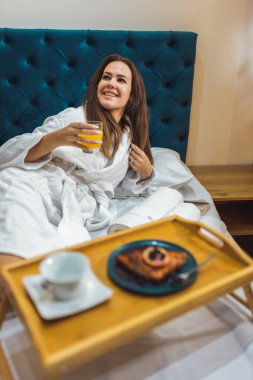 Güzel bir kadın otel odasında kahvaltısını yapıyor..
