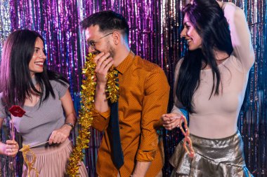 Gece kulübünde yılbaşını kutlayan üç arkadaş. Komik gözlükler ve bıyıklar takıyorlar..