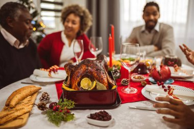 Kızarmış hindiyi masanın üzerine yakın çekim. Afro-Amerikan ailesi Noel ve Şükran Günü yemeği yiyor..