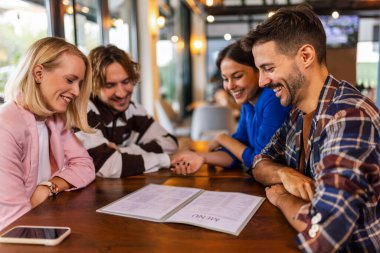 Arkadaşlar restorandaki menüye bakıp ne yiyeceklerini seçiyorlar..