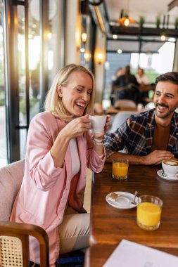 Genç ve neşeli bir kadın restoranda sıcak bir şeyler içiyor..