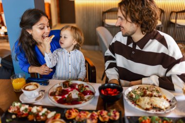 Üç kişilik bir aile lezzetli bir restoranda yemek yiyor. Yiyecek ve içecek konsepti.