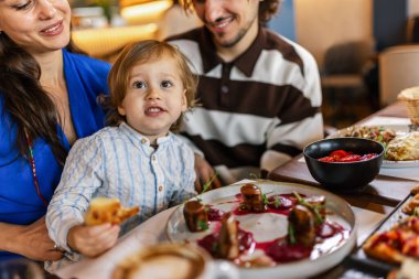 Üç kişilik bir aile lezzetli bir restoranda yemek yiyor. Yiyecek ve içecek konsepti.