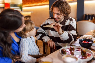 Üç kişilik bir aile lezzetli bir restoranda yemek yiyor. Yiyecek ve içecek konsepti.