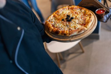 Tahta üzerinde pizza bir restoranda bir garson tarafından servis edilir. Lezzetli görünümlü pizza. Yiyecek ve içecek konsepti.