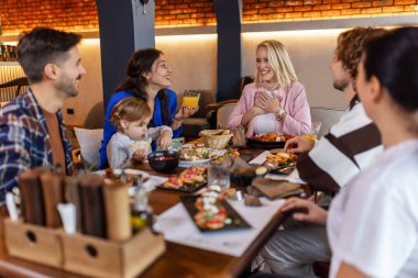 Aile ve arkadaşlar lezzetli yemekler yemek, konuşmak, içmek ve takılmak için bir restoranda toplandılar..
