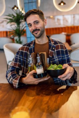 Lokantada elinde yağ, biber ve peçete tutacağı tutan bir adam.