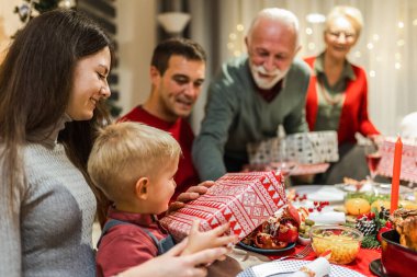 Büyükbabalar torunlarına Noel arifesinde hediye veriyorlar. Aile yemek yiyor..