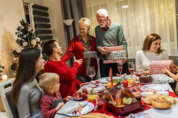 Büyükbabalar torunlarına Noel arifesinde hediye veriyorlar. Aile yemek yiyor..