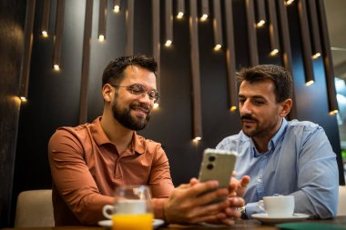 İki meslektaş kahve dükkanında takılıyor. Telefonda birlikte çalışıyoruz..