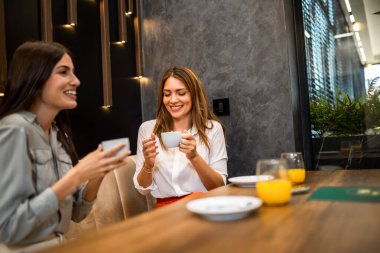 Restoranda en iyi iki kız arkadaş takılıyor. Kahve ve portakal suyu içiyorum. Dedikodu yaparlar, gülerler ve eğlenirler..