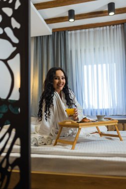 Güzel bir kadın otel odasında kahvaltısını yapıyor..