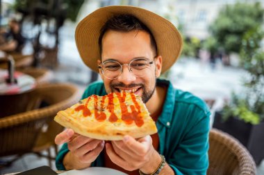 Lezzetli pizza yiyen yakışıklı bir gencin portresi..
